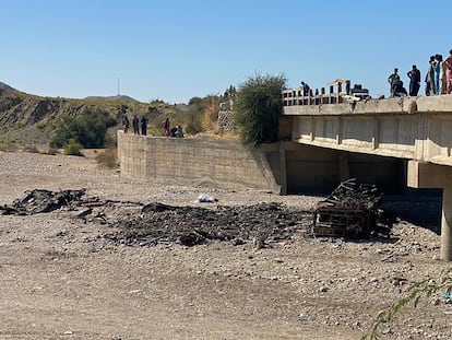Un grupo de personas observa los restos del autobús que este domingo ha caído por un puente en el distrito de Lasbela, en Pakistán.