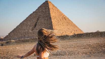 Una joven turista posa junto a una de las pirámides de Giza (Egipto).