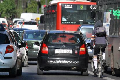 Un ciclista circula entre coches y autobuses en la calle de Russafa de Valencia.