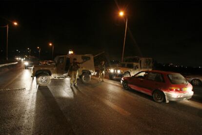 Policías y sanitarios en torno al coche de los colonos, en el que están señalados los impactos de bala.