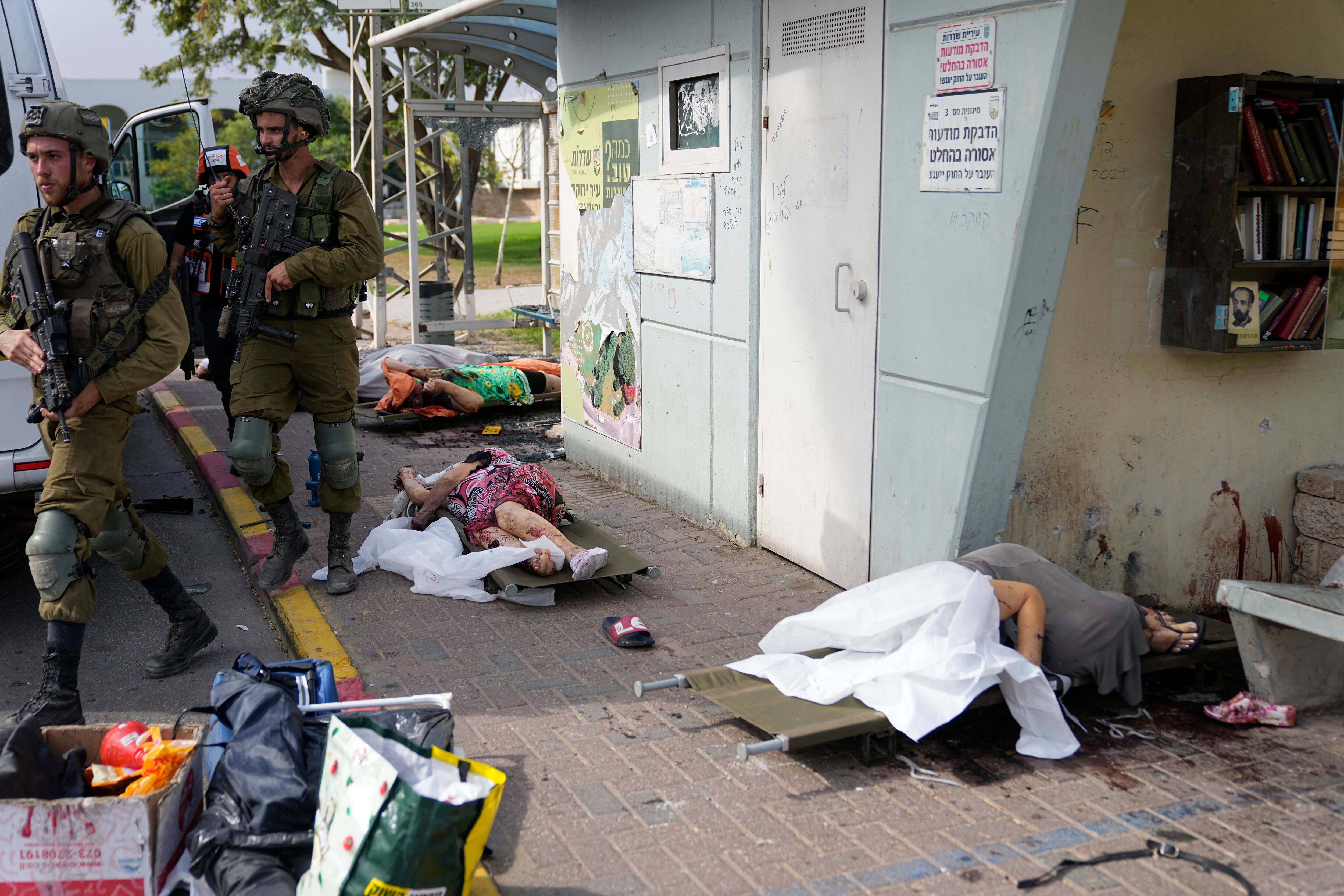 Soldados israelíes caminan junto a civiles asesinados por las milicias palestinas de Hamás en Sderot, Israel, el 7 de octubre de 2023. 