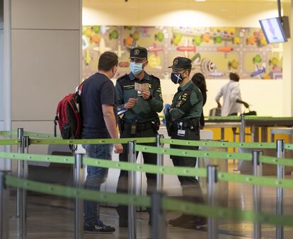 Dos agentes de la Guardia Civil piden la documentacin a un viajero, antes del control de seguridad de la Terminal 1 del aeropuerto Adolfo Surez Madrid, esta tarde.