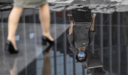 Un hombre con mascarilla se refleja en un charco en una calle de Guangzhou (China).