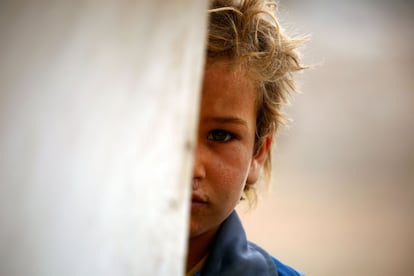 A displaced Syrian child, who fled the countryside surrounding the Islamic State (IS) group stronghold of Raqa, stands at a temporary camp in the village of Ain Issa on April 28, 2017. / AFP PHOTO / DELIL SOULEIMAN