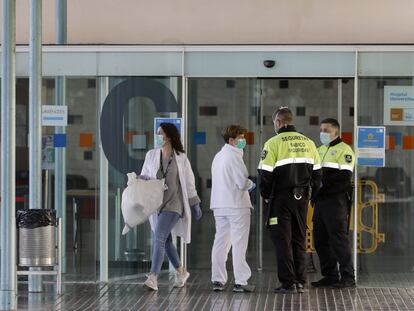 Dos agentes de seguridad junto a dos enfermeras en la entrada principal del Hospital del Mar de Barcelona. EFE / Andreu Dalmau