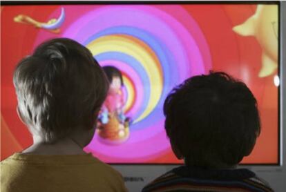 Dos ni&ntilde;os frente auna pantalla de televisi&oacute;n. 