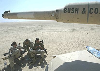 <i>Marines</i> de Estados Unidos descansan, ayer en el desierto de Kuwait, junto a un carro de combate M1A1 Abrams.