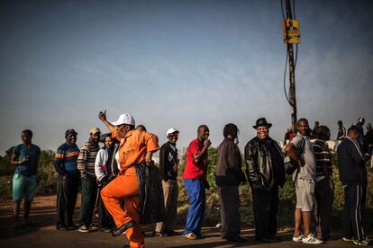 Un trabajador municipal baila mientras los votantes hacen copla en el centro electoral en Umlazi, Durban, Sudáfrica.