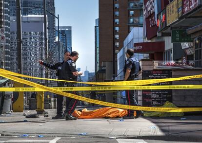 Agentes de la policía, junto a un cuerpo cubierto en la acera, después de que una camioneta arrollara a una multitud de peatones en Toronto.