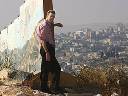 Uri Bank, junto al muro de Gilo, contempla la aldea palestina de Beit Yala. En la otra imagen, Meir Turjeman junto a los sacos terreros que protegen la entrada de una guardería.