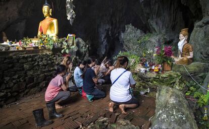 Familiares de los niños atrapados rezan en la zona de la cueva de Tham Luang este jueves.