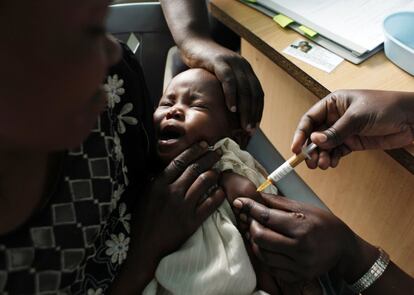 La malaria es una de las enfermedades tropicales más diagnosticada España. En la imagen, una madre sostiene a su bebé mientras le vacunan contra la malaria en Kenia.