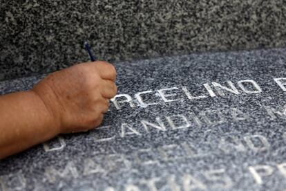 Una mujer pinta las letras de una lápida, en el cementerio de La Almudena de Madrid.