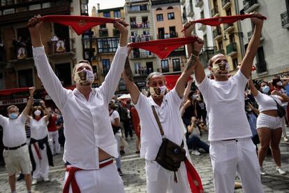 Varias personas, vestidas de blanco y rojo, alzan sus pañuelos al aire a las 12.00 durante el 'no chupinazo' de los Sanfermines de este año.