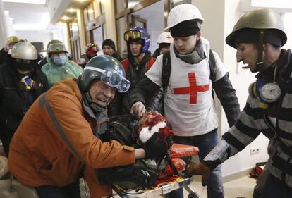 Un herido en la batalla campal de hoy llega al hotel Ucrania que se ha convertido en  un improvisado hospital de campa&ntilde;a y morgue.