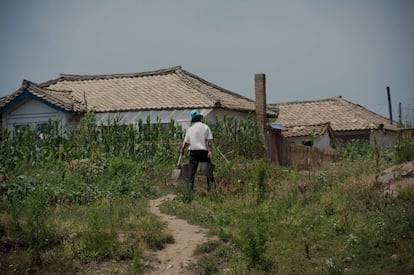 Una mujer norcoreana carga cubos llenos de agua del río, cerca de Sinuiju.