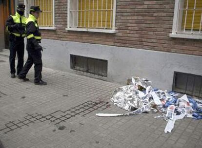 Dos policías municipales de Zaragoza miran el lugar donde un hombre de 29 años ha muerto de varios disparos realizados por un individuo que se ha entregado a la policía.