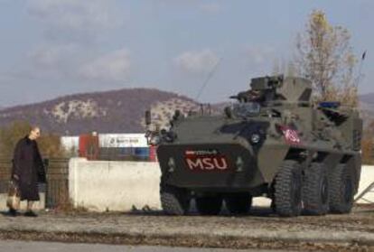 Una mujer pasa por delante de un vehículo blindado de las tropas austriacas de la OTAN en Mitrovica, en la provincia de Kosovo. EFE/Archivo