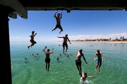 Un grupo de nadadores saltan de un embarcadero para escapar del calor del verano en la playa de Henley, al oeste de Adelaida (Australia).