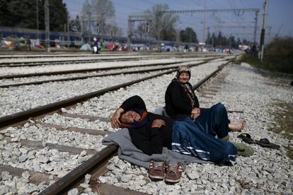 Una pareja de ancianos migrantes toma un descanso en las vías del ferrocarril en un campamento improvisado en la frontera entre Grecia y Macedonia, cerca de la localidad de Idomenii (Grecia).