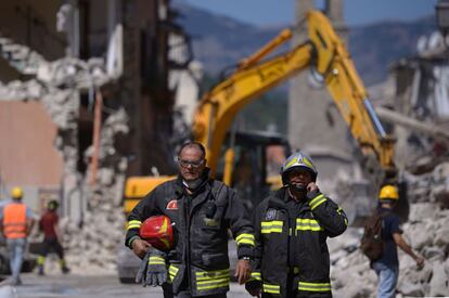 Bomberos delante de una excavadora usada para buscar víctimas debajo de los escombros producidos por un terremoto en Amatrice (centro de Italia). 
