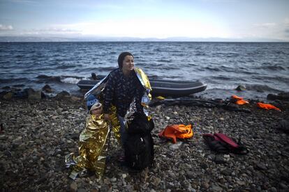 FILE - In this Friday, Oct. 2 , 2015 file photo, A Syrian refugee woman and child are wrapped with thermal blankets to shelter from the cold after arriving on a dinghy from the Turkish coast to the northeastern Greek island of Lesbos. The U.N. agency for children says more than 80 percent of Syria's children have been harmed by the five-year-old conflict, including growing numbers forced to work, join armed groups or marry young because of widening poverty. (AP Photo/Muhammed Muheisen, File)