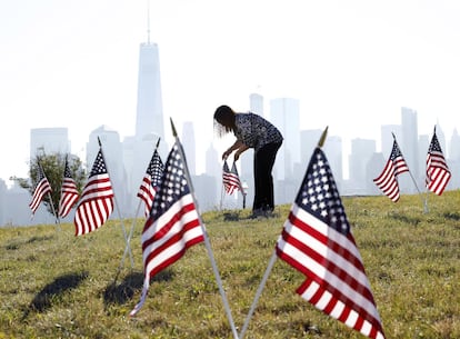 Yalenny Vargas coloca banderas para las celebraciones del 4 de julio en el Liberty State Park de Jersey City, N. J.