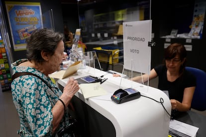 Una mujer entrega la documentación para ejercer el voto por correo en una oficina de Madrid.