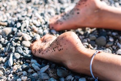 Una mujer con los pies en la playa.