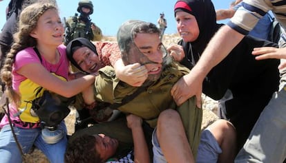 Diverses dones i una nena tracten d'arrabassar el menor dels braços del soldat israelià.