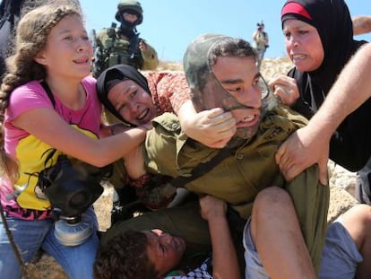 Varias mujeres y una niña tratan de arrebatar al menor de los brazos del soldado israelí.
