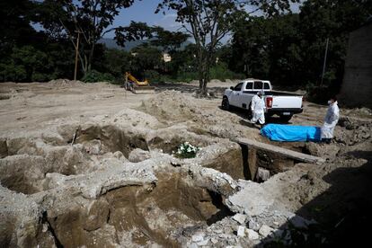 Trabajadores de una funeraria mueven el ataúd de una persona, víctima del coronavirus, en el cementerio de La Bermeja, en San Salvador.