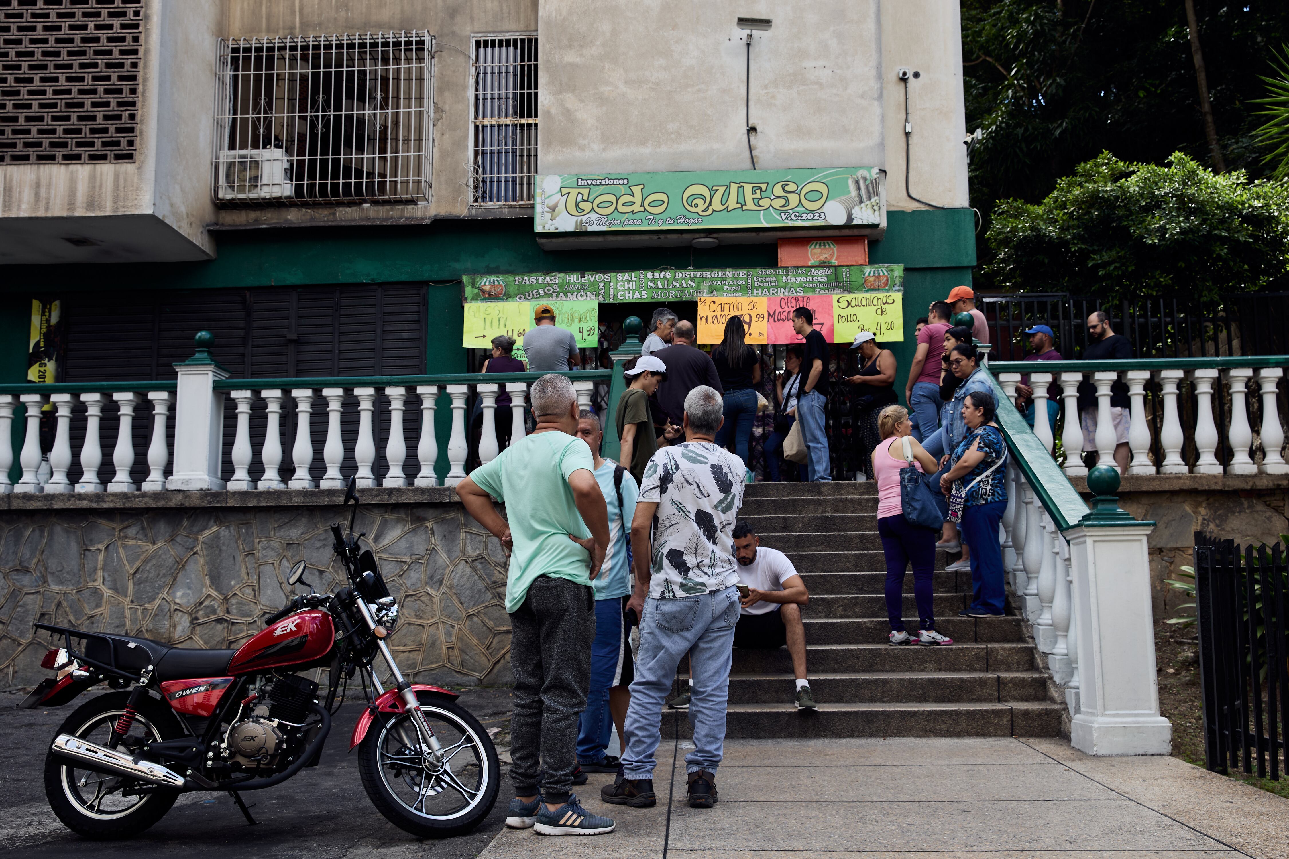 Personas hacen fila para comprar comida en una bodega.