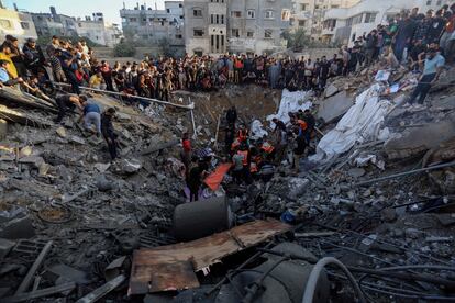 Una multitud de personas junto a los escombros de una casa destruida tras un ataque aéreo israelí sobre Gaza, este sábado. 