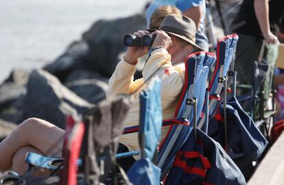 Un hombre sujeta sus prismáticos desde el sitio que ha conseguido para seguir el lanzamiento del cohete Falcon Heavy rocket en Cabo Cañaveral.