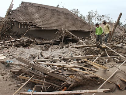 Dos personas caminan entre los restos de una casa destrozada por la erupción del volcán Semeru, en el municipio de Supiturang, en la isla indonesia de Java.