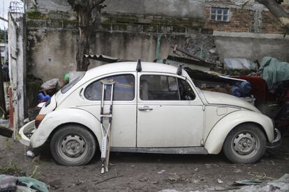 As muletas de Héctor ficam apoiadas em um Fusca enquanto ele ajuda a recuperar artigos pessoais da casa de um vizinho em Jojutla (México).