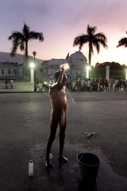 Uno de los niños refugiados en el campamento instalado frente al palacio presidencial intenta asearse en plena calle.