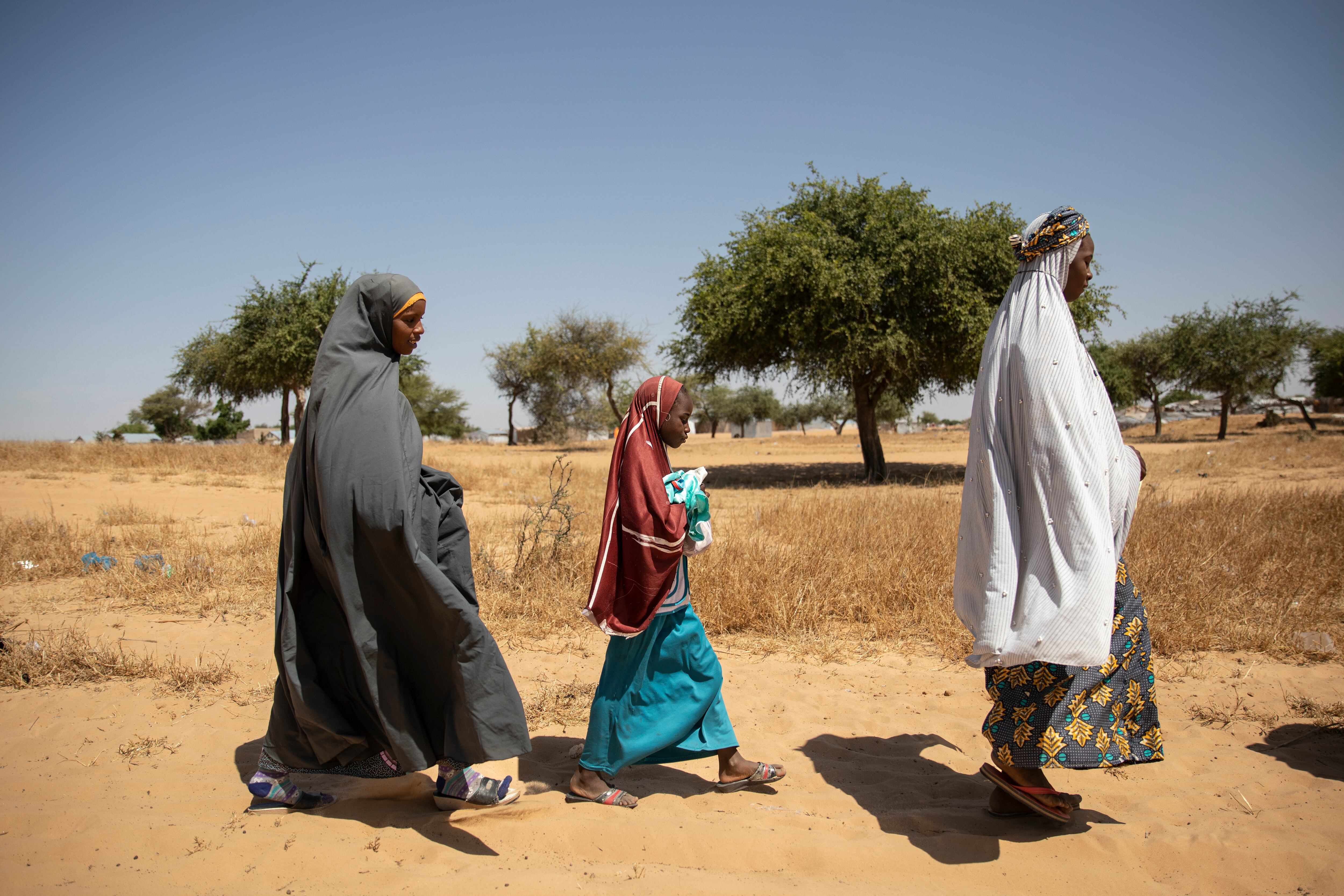 Roukaya lleva en brazos a Maimouna y Rachida, la madre de ambas, camina a su lado, de vuelta a casa, en el campo de refugiados de Dar es Salam. En este asentamiento viven más de 18.000 personas desplazadas a la fuera por el terrorismo o por fenómenos climáticos extremos.