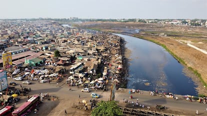 Vista aérea de Agbogbloshie. A un lado del río, los asentamientos del barrio donde los trabajadores del vertedero se hacinaron tras ser desalojados. Al otro, los terrenos que el gobierno de Ghana recuperó en julio de 2021. Las autoridades han levantado un muro para impedir que los 'quemadores' de cables vuelvan a instalarse.