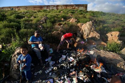 Una familia quema basura cerca de la frontera entre México y Estados Unidos, a las afueras de Tijuana (México).