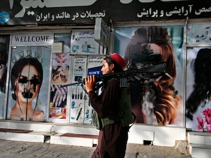 Un talibán pasa por delante de un salón de belleza con las imágenes de mujeres pintadas con aerosol, en Kabul este 18 de agosto.