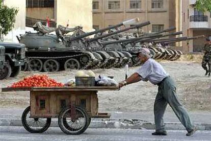 Un vendedor de verduras pasa por delante de una fila de tanques en la ciudad libanesa de Tiro.