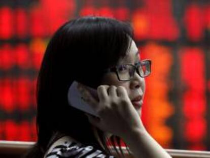 Una agente habla por teléfono frente a una pantalla con los resultados de la Bolsa de Bangkok.