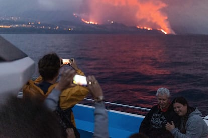 Dos turistas fotografían el volcán, al fondo, desde el barco Fancy.