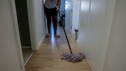 Una mujer friega el pasillo de casa en Madrid.
