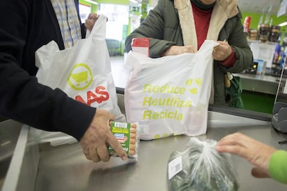 Unos clientes de un supermercado llenan bolsas de plástico con la compra, en Sevilla. Cada año se utilizan en el mundo cinco billones de bolsas plásticas desechables, según datos de la ONU.