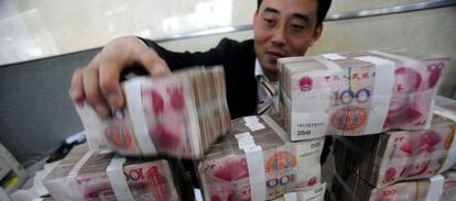 Un empleado de un banco en Hefei (centro de China) manipula paquetes de billetes de yuanes. 