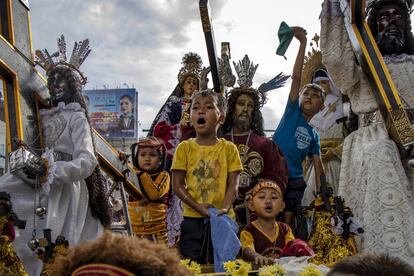 Cuatro niños a bordo de una carroza durante el desfile de la Fiesta del Nazareno Negro, en Manila (Filipinas).