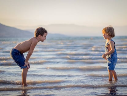 Dos hermanos juegan en la playa. 